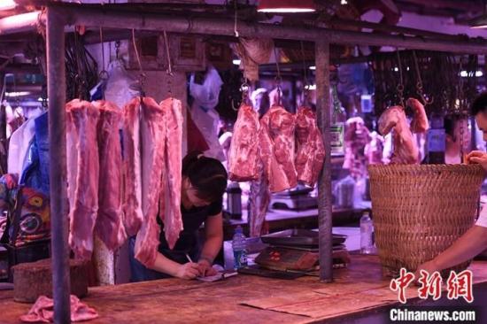 资料图：农贸市场内的商家挂满充足的猪肉。中新社记者 陈超 摄